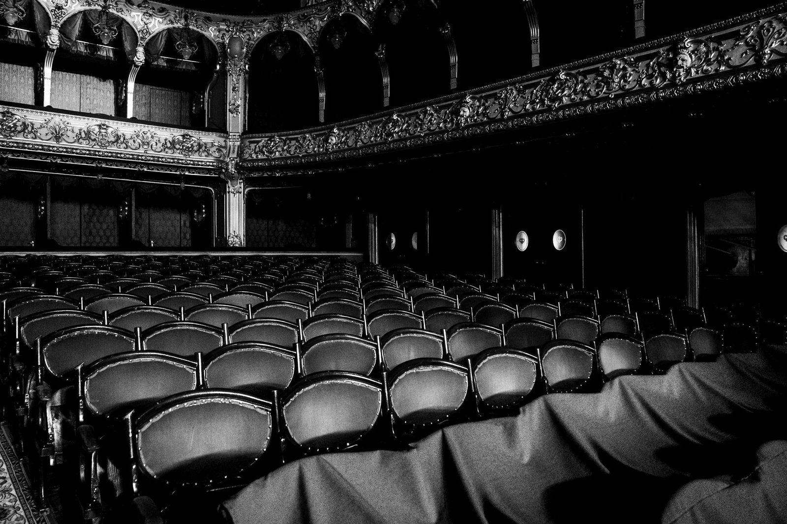 Sala de cine antigua vacía, en blanco y negro, con butacas y palcos ornamentados.